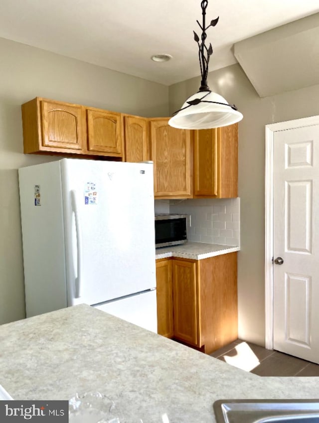 kitchen featuring backsplash, hanging light fixtures, and white refrigerator