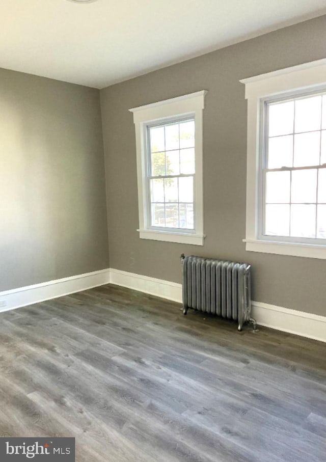 unfurnished room featuring radiator and hardwood / wood-style flooring