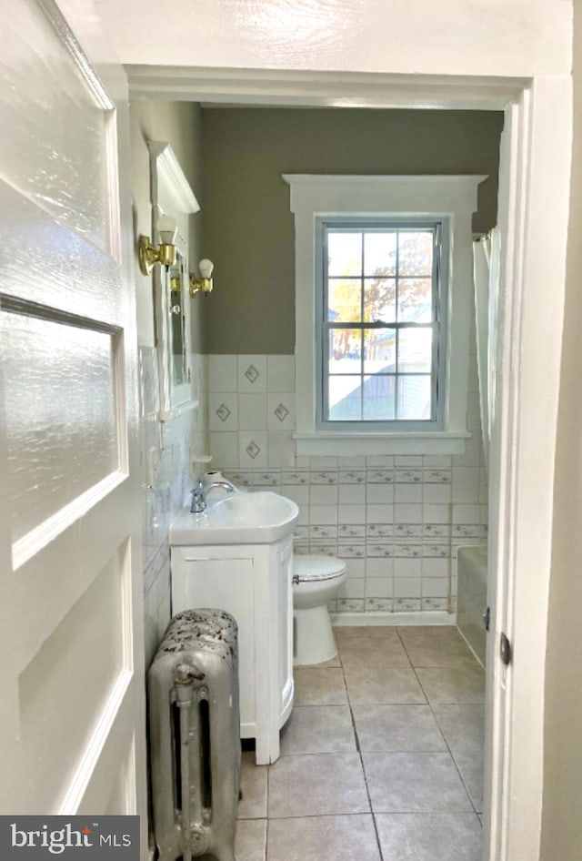 full bathroom featuring radiator, toilet, tile patterned flooring, tile walls, and vanity