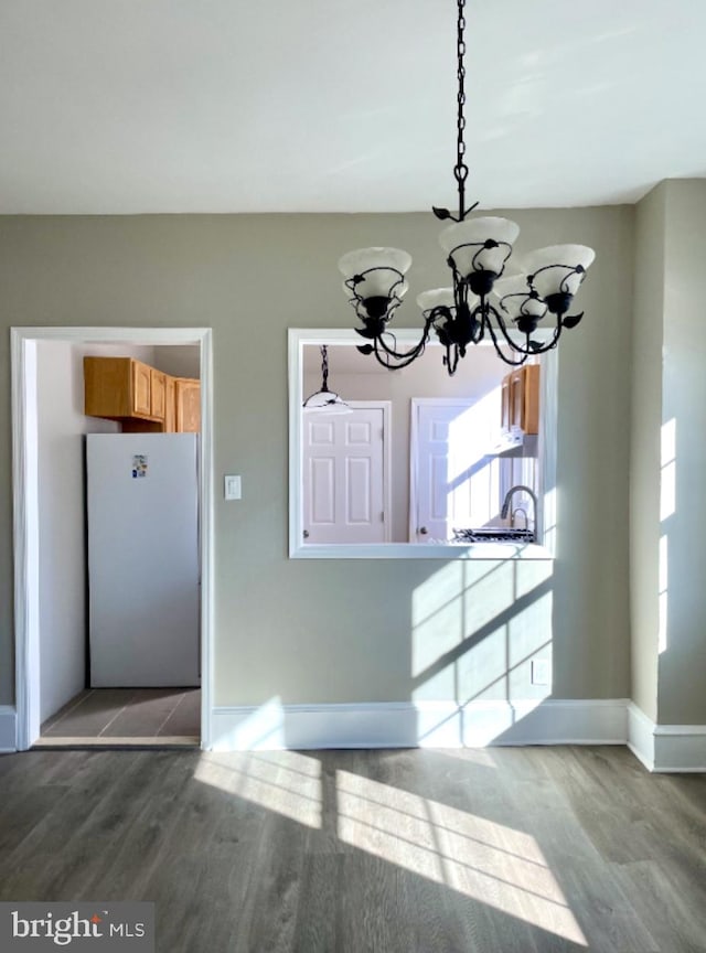 unfurnished dining area with a wealth of natural light, an inviting chandelier, and hardwood / wood-style floors