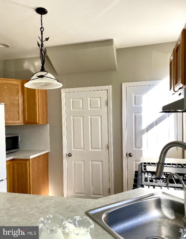 kitchen with backsplash, white fridge, and decorative light fixtures