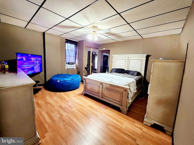 bedroom featuring ceiling fan, light hardwood / wood-style floors, and a paneled ceiling