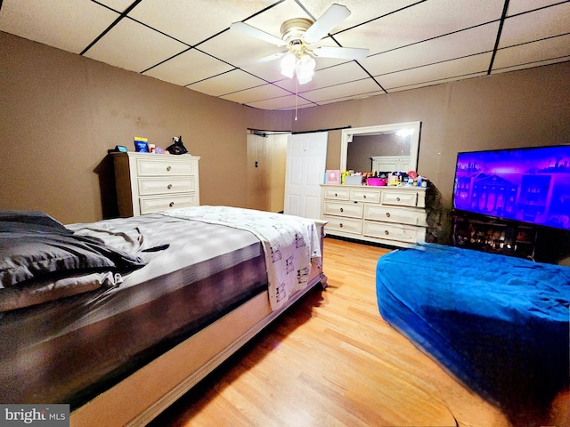 bedroom with light hardwood / wood-style floors, a drop ceiling, and ceiling fan