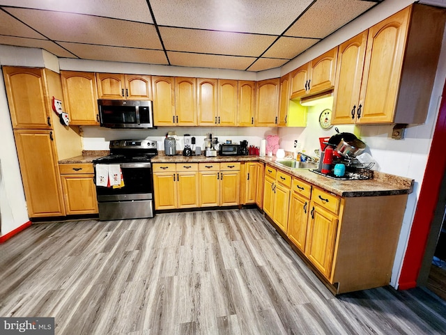 kitchen featuring sink, light hardwood / wood-style flooring, a paneled ceiling, and stainless steel appliances