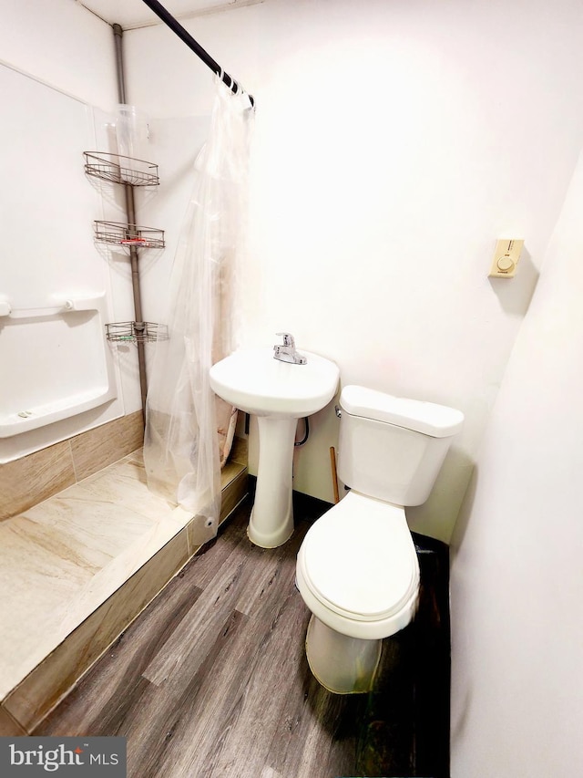 bathroom with toilet, hardwood / wood-style floors, and curtained shower