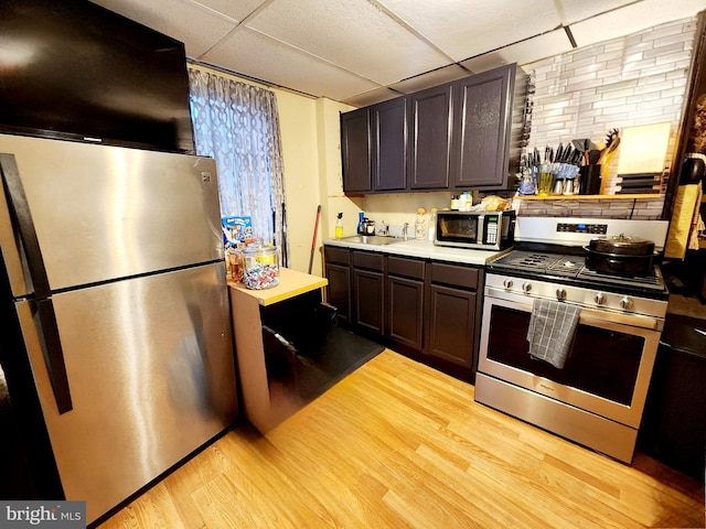 kitchen featuring light hardwood / wood-style floors, a drop ceiling, dark brown cabinetry, and stainless steel appliances