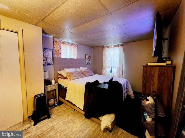 bedroom with light carpet and a paneled ceiling