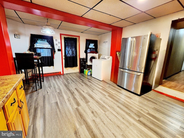 kitchen with washer / dryer, stainless steel fridge, a drop ceiling, and light wood-type flooring