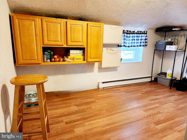 interior space with a baseboard heating unit, light wood-type flooring, and a textured ceiling