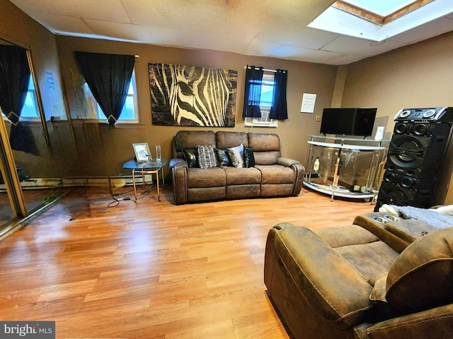 living room featuring light hardwood / wood-style floors, baseboard heating, and a skylight