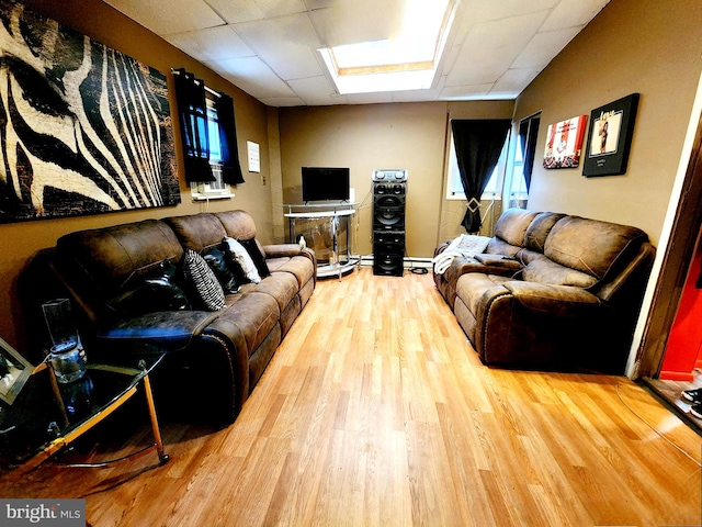 living room featuring a skylight, a paneled ceiling, and hardwood / wood-style floors