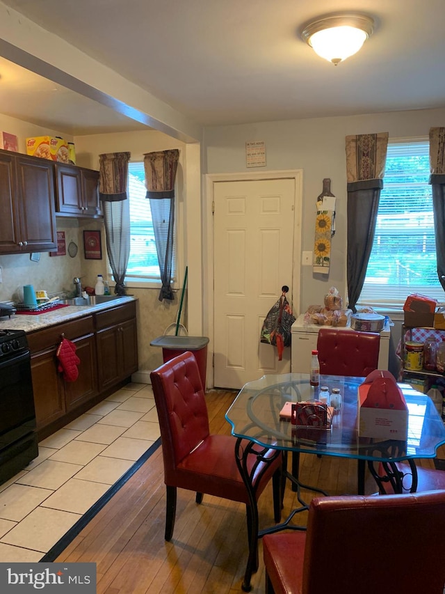 kitchen with backsplash, black stove, light hardwood / wood-style floors, and dark brown cabinetry