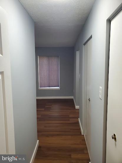 corridor featuring dark hardwood / wood-style floors and a textured ceiling