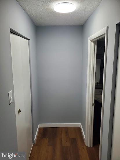 hallway featuring a textured ceiling and dark hardwood / wood-style flooring