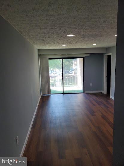 empty room featuring dark wood-type flooring and a textured ceiling