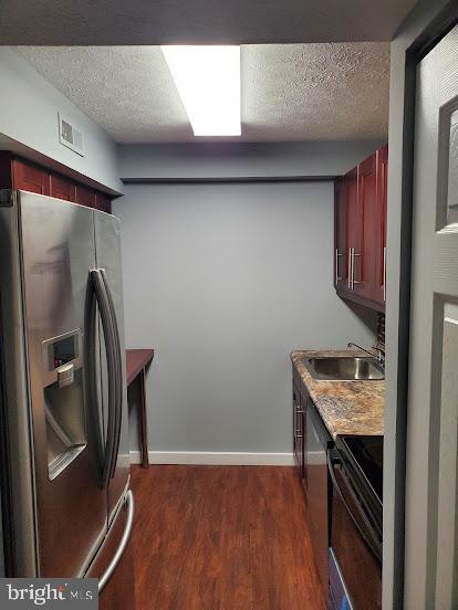 kitchen featuring dark hardwood / wood-style flooring, sink, stainless steel appliances, and a textured ceiling