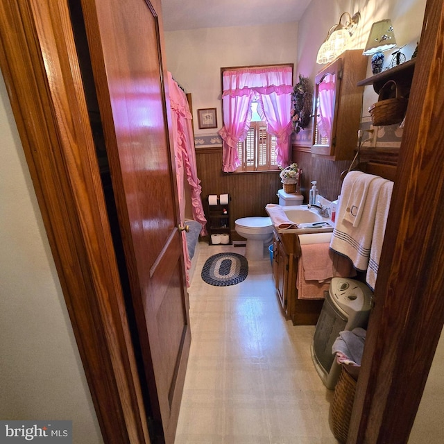 bathroom featuring toilet, wainscoting, wooden walls, vanity, and tile patterned floors