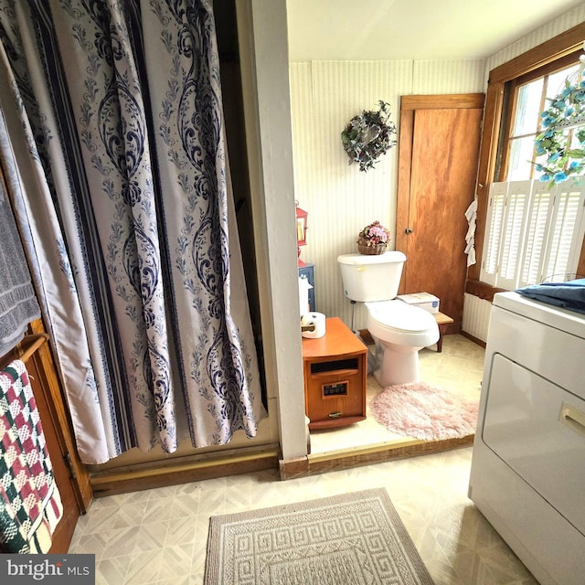 bathroom with washer / clothes dryer, toilet, and tile patterned floors