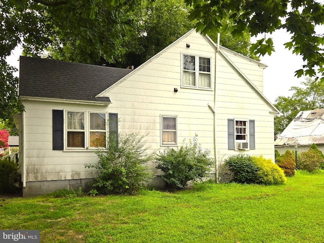 exterior space with roof with shingles, a lawn, and cooling unit