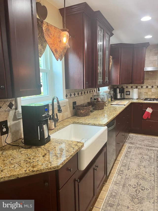 kitchen with pendant lighting, light stone countertops, sink, tasteful backsplash, and stainless steel dishwasher