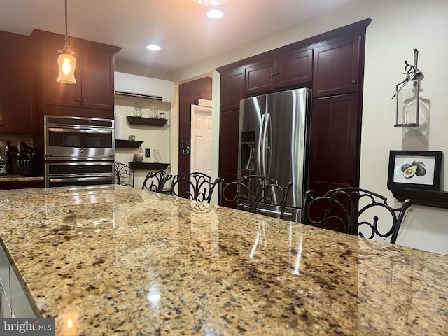 kitchen featuring appliances with stainless steel finishes, hanging light fixtures, and light stone countertops