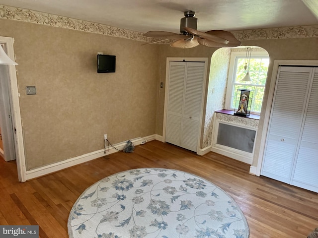 bedroom with ceiling fan, two closets, and hardwood / wood-style flooring