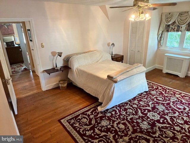 bedroom with radiator, hardwood / wood-style floors, ceiling fan, and a closet