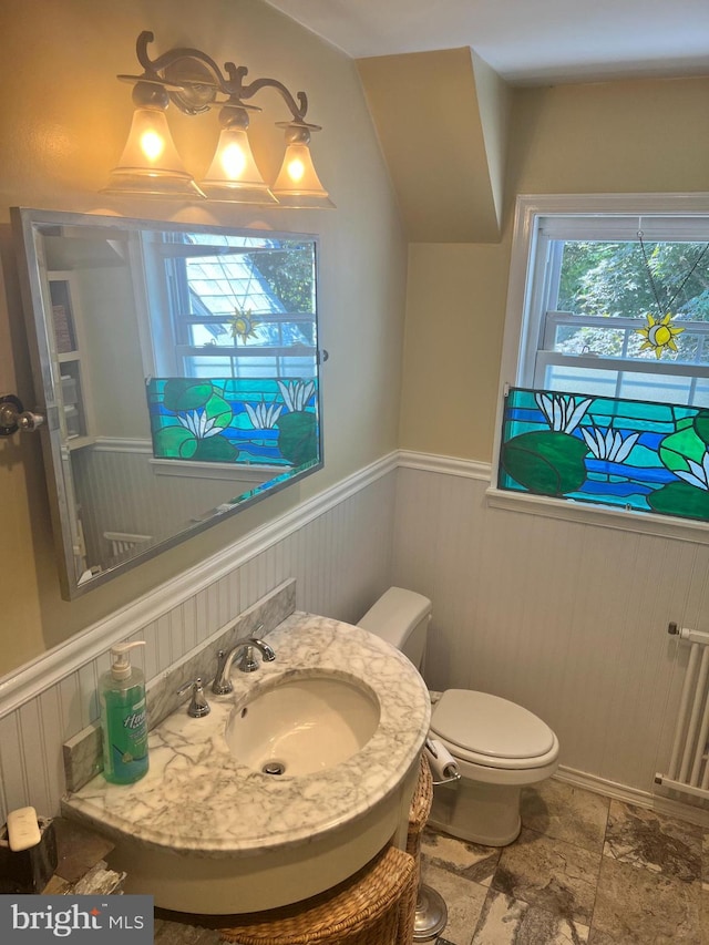 bathroom featuring toilet, vaulted ceiling, radiator heating unit, sink, and tile patterned floors