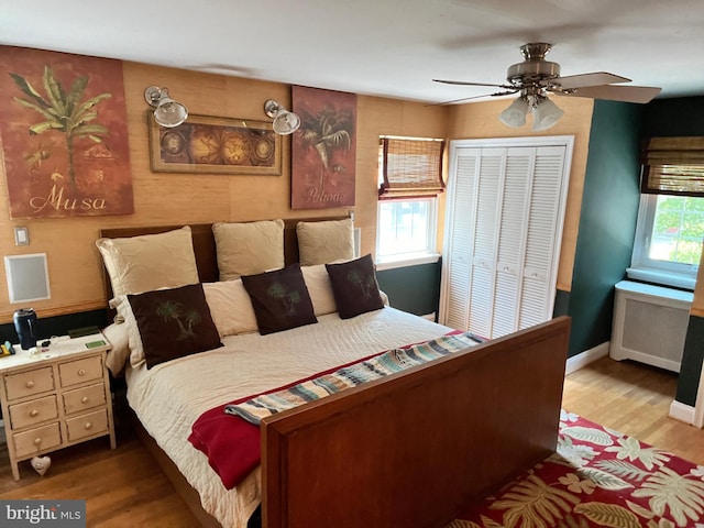 bedroom with ceiling fan, a closet, hardwood / wood-style flooring, and radiator heating unit