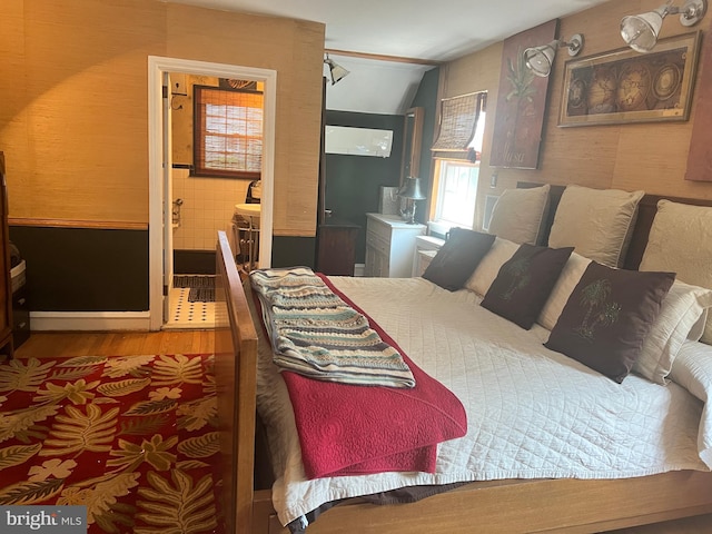 bedroom with hardwood / wood-style flooring and connected bathroom