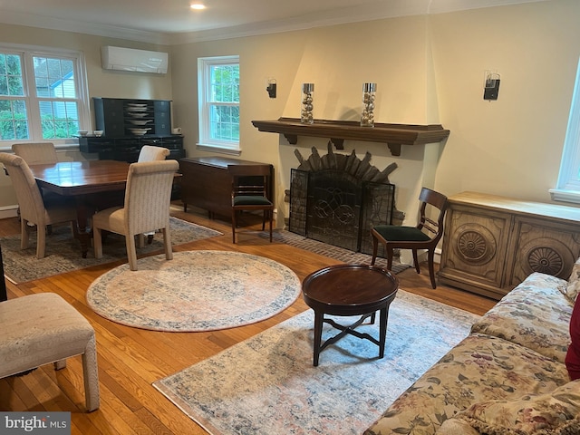 living room featuring an AC wall unit, crown molding, and light hardwood / wood-style floors