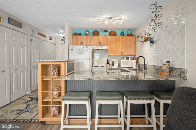 kitchen with tasteful backsplash, sink, track lighting, white appliances, and light brown cabinetry