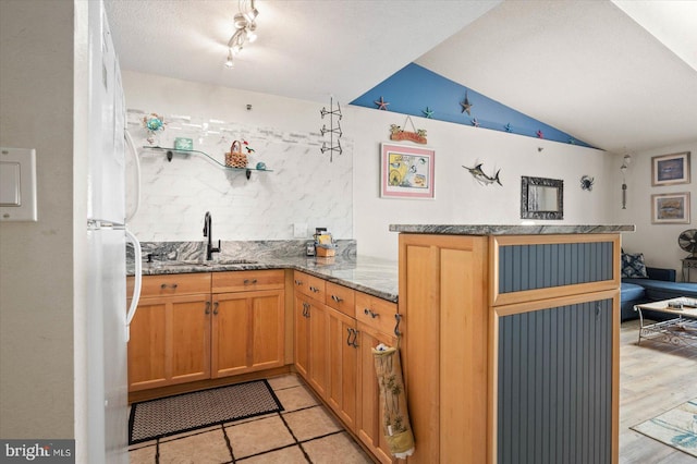 kitchen featuring a textured ceiling, rail lighting, kitchen peninsula, and dark stone counters