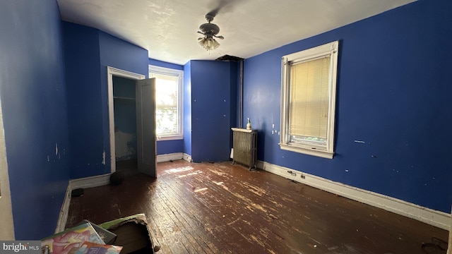 unfurnished bedroom featuring radiator, ceiling fan, and dark wood-type flooring