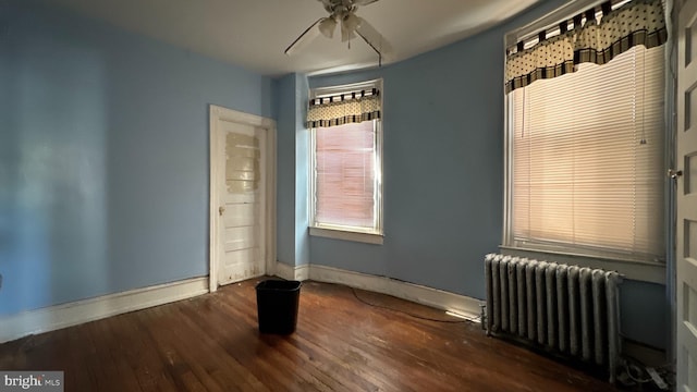 unfurnished room with ceiling fan, dark hardwood / wood-style flooring, and radiator heating unit