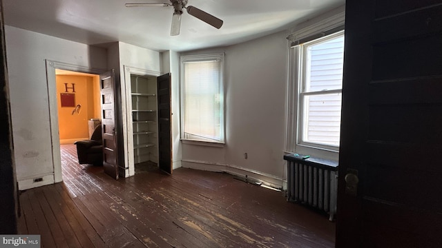 unfurnished bedroom with radiator, dark hardwood / wood-style floors, ceiling fan, and a closet