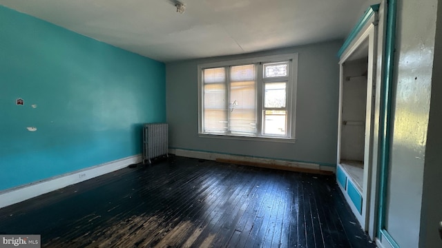 spare room with radiator and dark hardwood / wood-style flooring