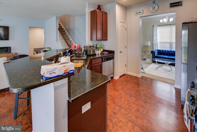 kitchen with kitchen peninsula, a kitchen breakfast bar, a notable chandelier, dishwasher, and dark hardwood / wood-style flooring