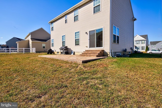 rear view of house with a yard, a patio, fence, and entry steps