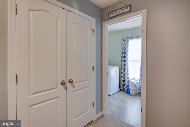 hall with washer / dryer, a healthy amount of sunlight, and light hardwood / wood-style flooring