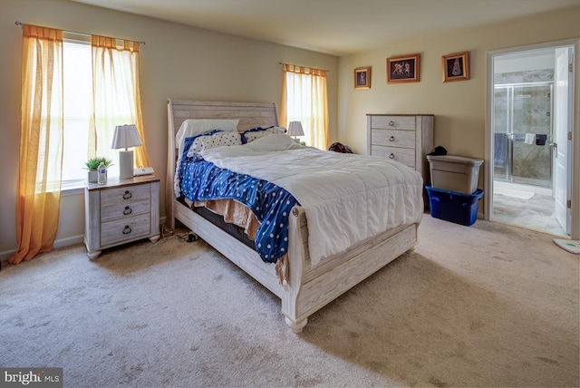 bedroom with multiple windows, light carpet, and connected bathroom