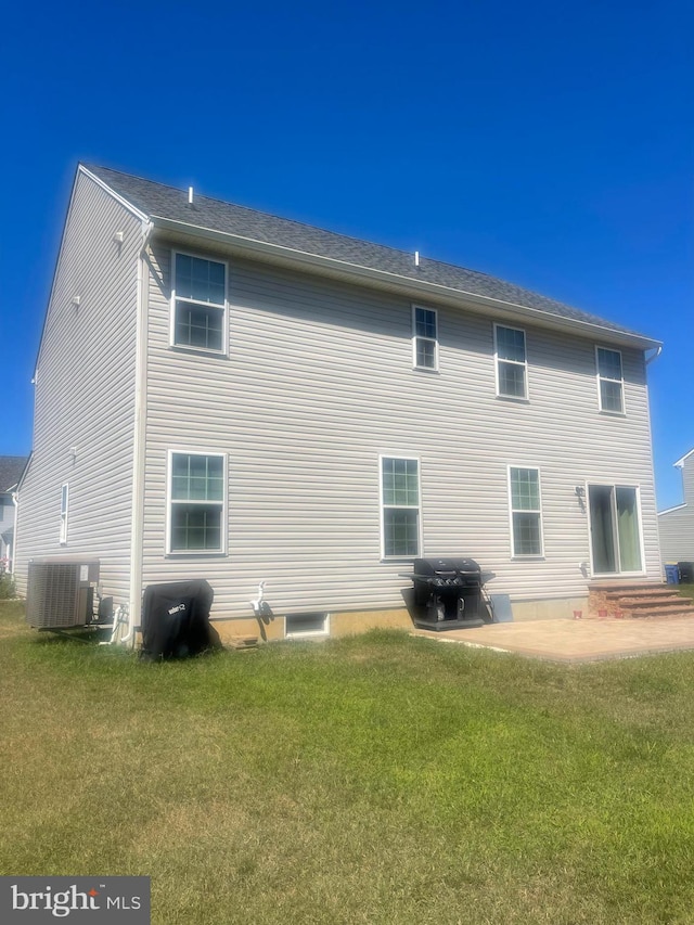 rear view of property featuring central air condition unit, a lawn, and a patio