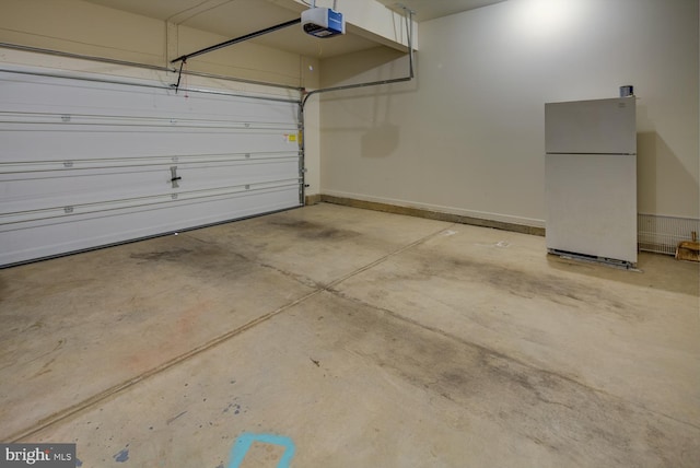 garage with a garage door opener and white fridge