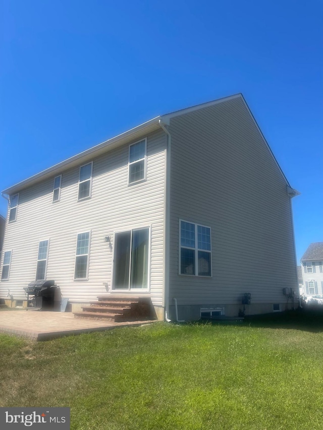 back of property with a lawn and a patio area