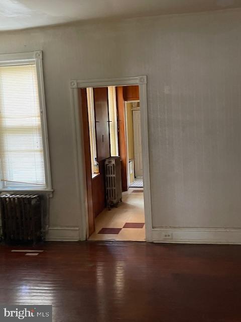 empty room with hardwood / wood-style floors, radiator heating unit, and a wealth of natural light