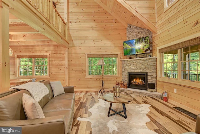 living room with a stone fireplace, wood walls, wood-type flooring, and high vaulted ceiling