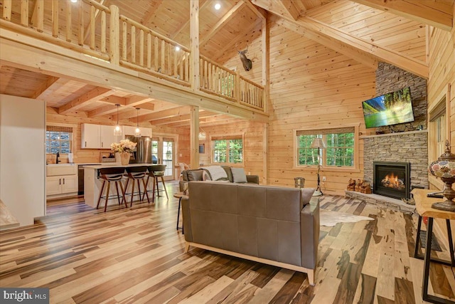 living room featuring high vaulted ceiling, light wood-type flooring, wooden walls, and wooden ceiling