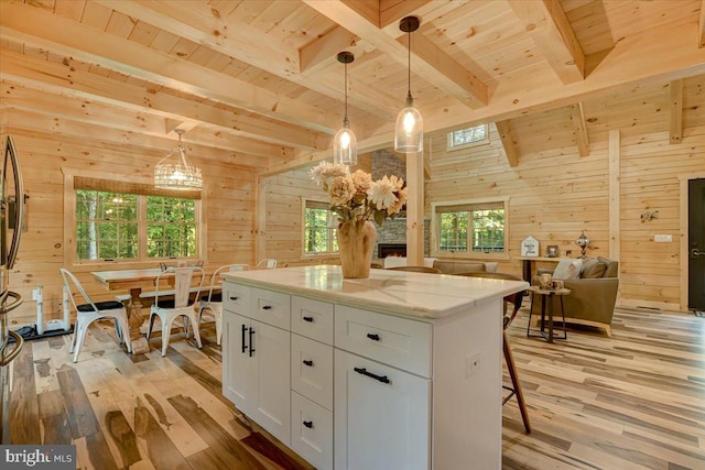 kitchen featuring wood walls, light hardwood / wood-style flooring, wooden ceiling, and white cabinets