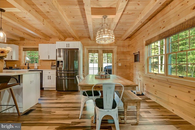 interior space featuring wood walls, a chandelier, wooden ceiling, beam ceiling, and light hardwood / wood-style floors