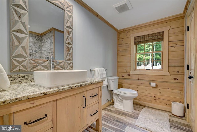 bathroom with wood walls, toilet, vanity, hardwood / wood-style floors, and ornamental molding